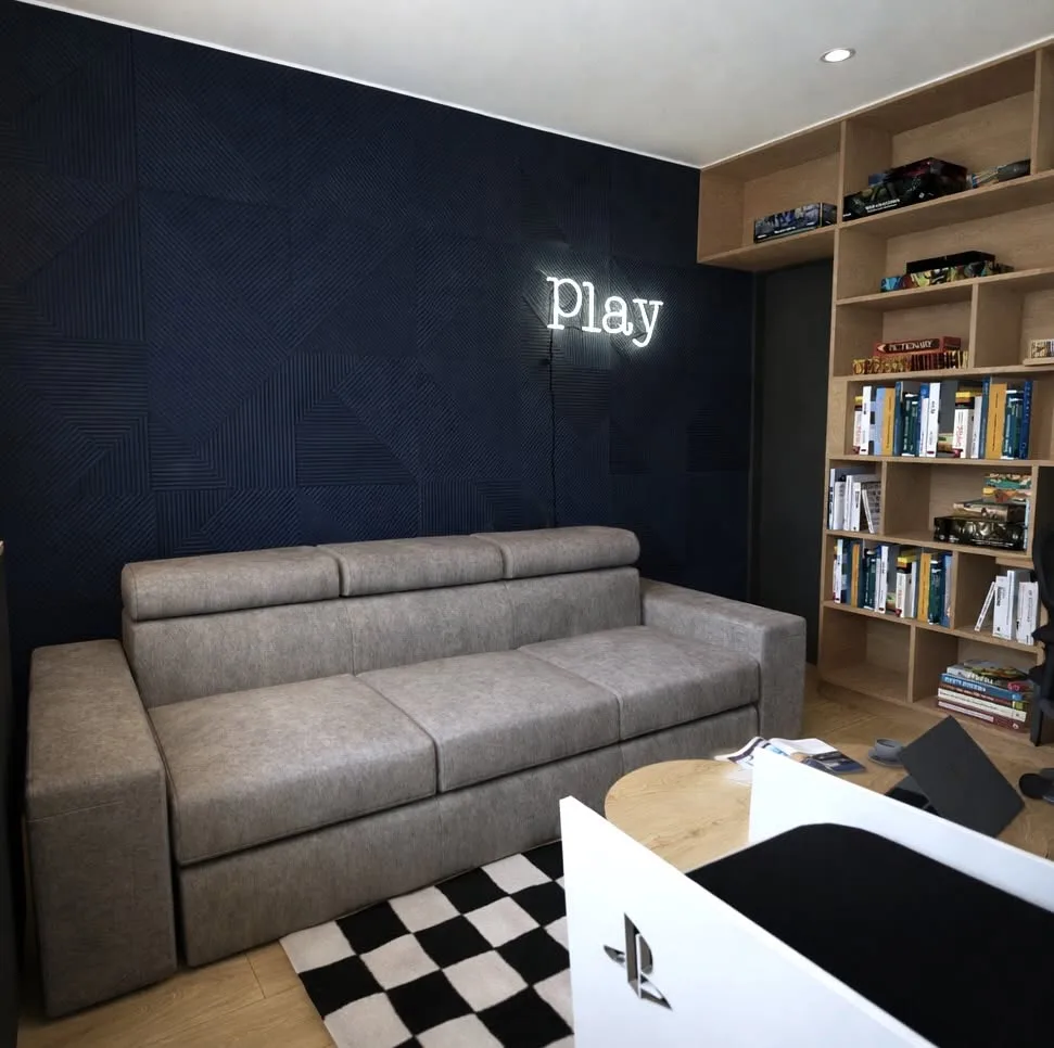 Pokój gier z granatową ścianą, neonem Play i szachownicą na podłodze